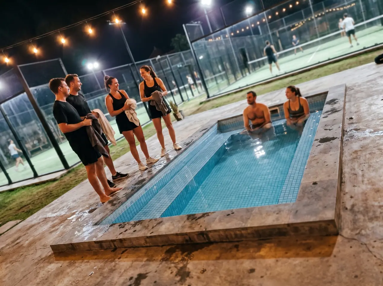 Canggu padel club at night: players waiting their turn at the sunken mosaic cold plunge pool